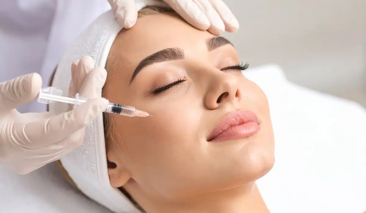 A medical professional's gloved hands administering a Botox injection near the eye area of a patient, demonstrating the precision of the cosmetic facial treatment.
