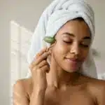 A woman using a facial roller as part of a skincare ritual, symbolizing the personalized and evolving future of non-surgical facial rejuvenation.